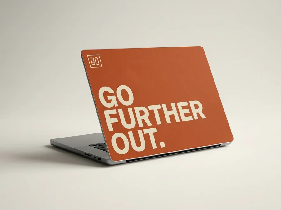 Laptop with a burnt-orange cover reading Go Further Out in cream type