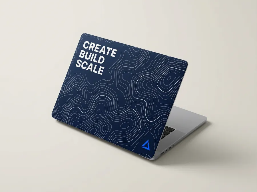 Laptop with a navy contour-line cover reading Create Build Scale