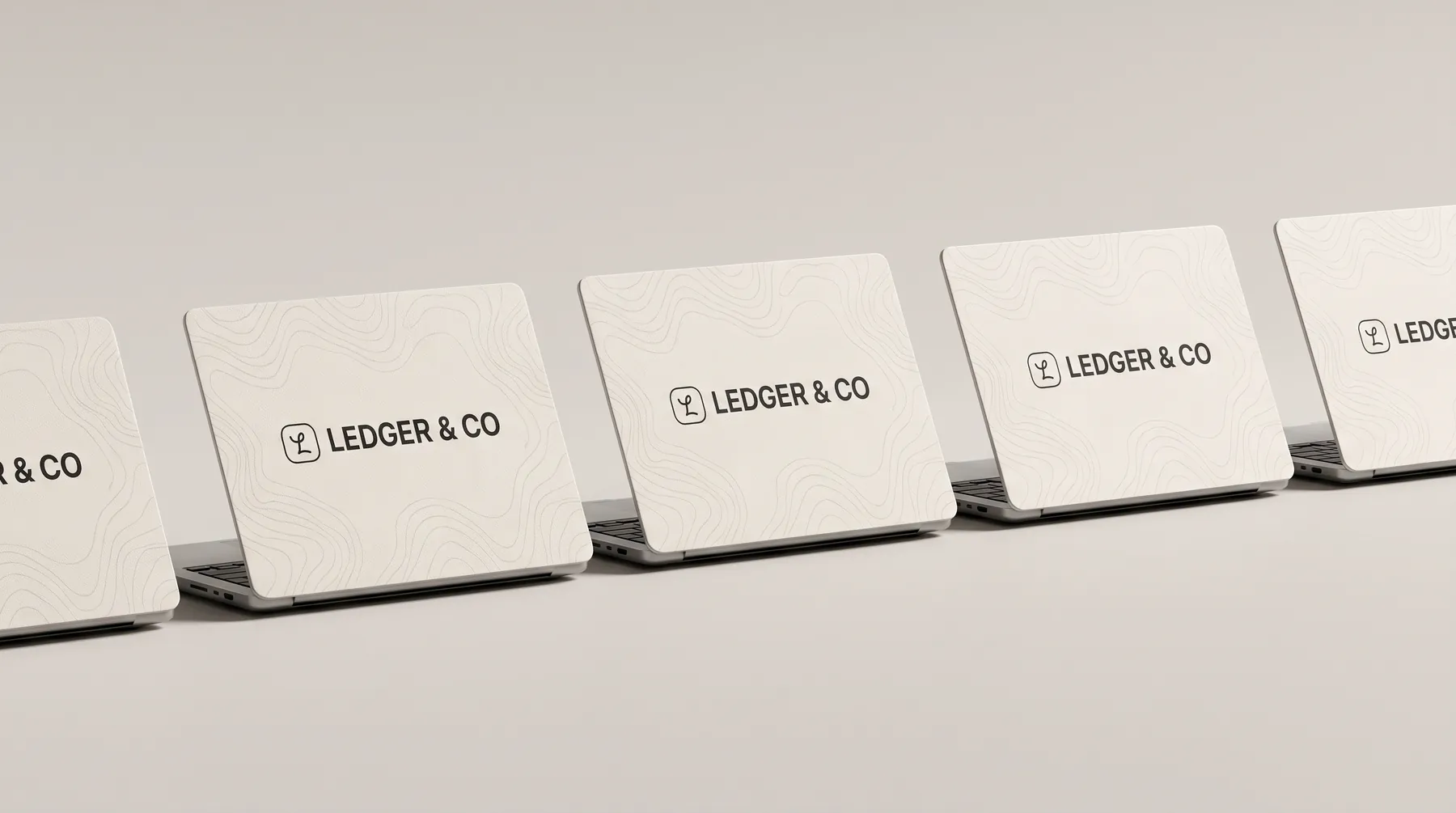 Five identical laptops in a row, each wearing the same Ledger & Co cover